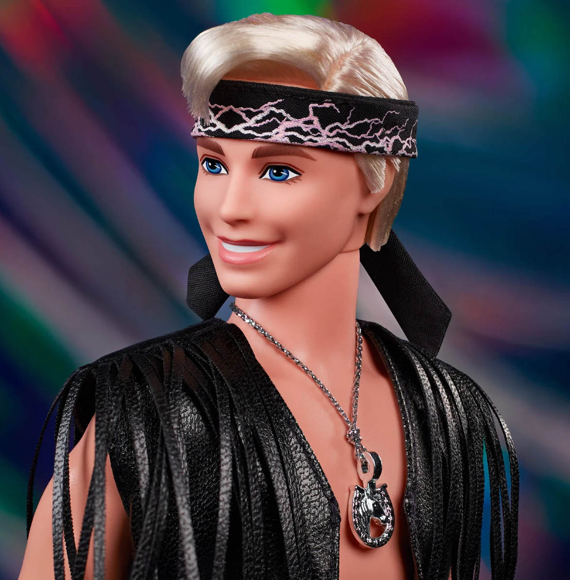 Ken Doll In Faux Fur Coat And Black Fringe Vest – Barbie The Movie head shot on coloured background